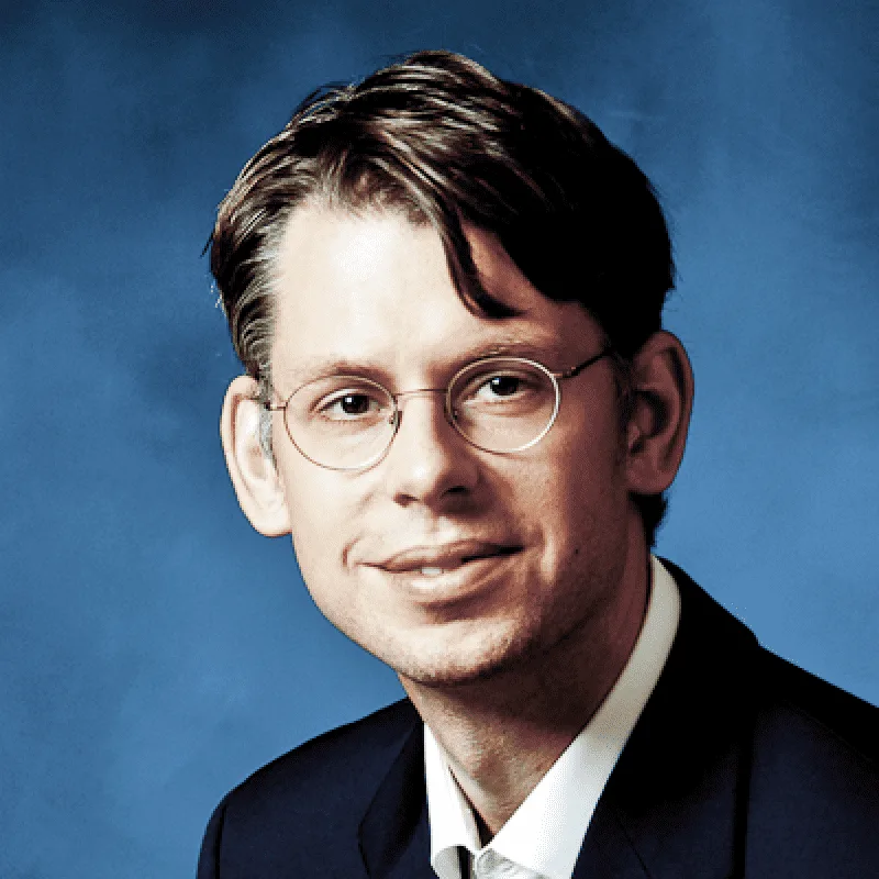 Porträt von Corvin Schmoller mit Brille vor blauem Hintergrund
