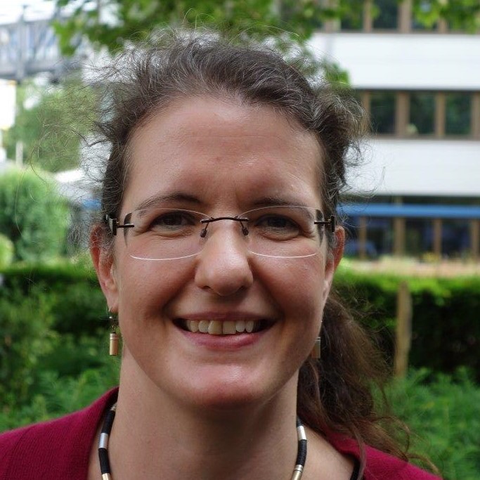 1. Deutscher Omega-3-Kongress – Omega-3-Vortragsaufzeichnungen 3 Portrait von Weis, Frau mit Brille und braunem Haar in rotem Oberteil vor grünem Hintergrund