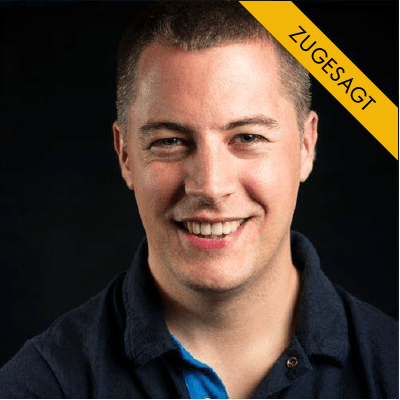 Jakob Hager, junger Mann mit dunklem Haar, dunklem Poloshirt und blauem Oberteil, vor schwarzem Hintergrund
