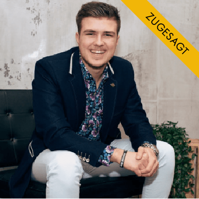 Nick Geringer, junger Mann mit dunklem Haar, dunklem Blazer und gemustertem Hemd, auf Stuhl sitzend