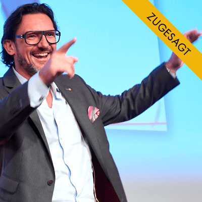 Porträt von Oliver Geisselhart, Mann mit Brille bei Vortrag vor blauem Hintergrund