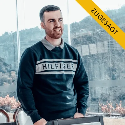 Porträt von David Hahn, Mann in dunklem Hilfiger-Pullover vor bergiger Kulisse