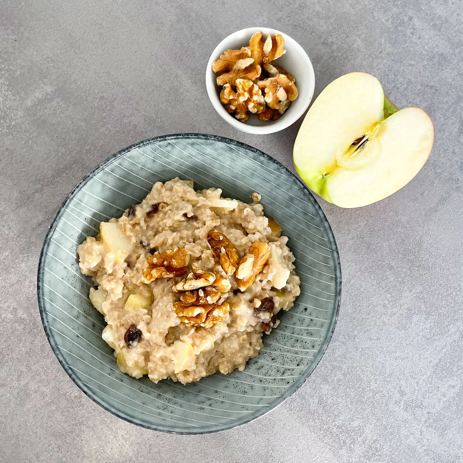 Apfel-Zimt-Rosinen-Porridge mit Walnüssen in grauer Schale