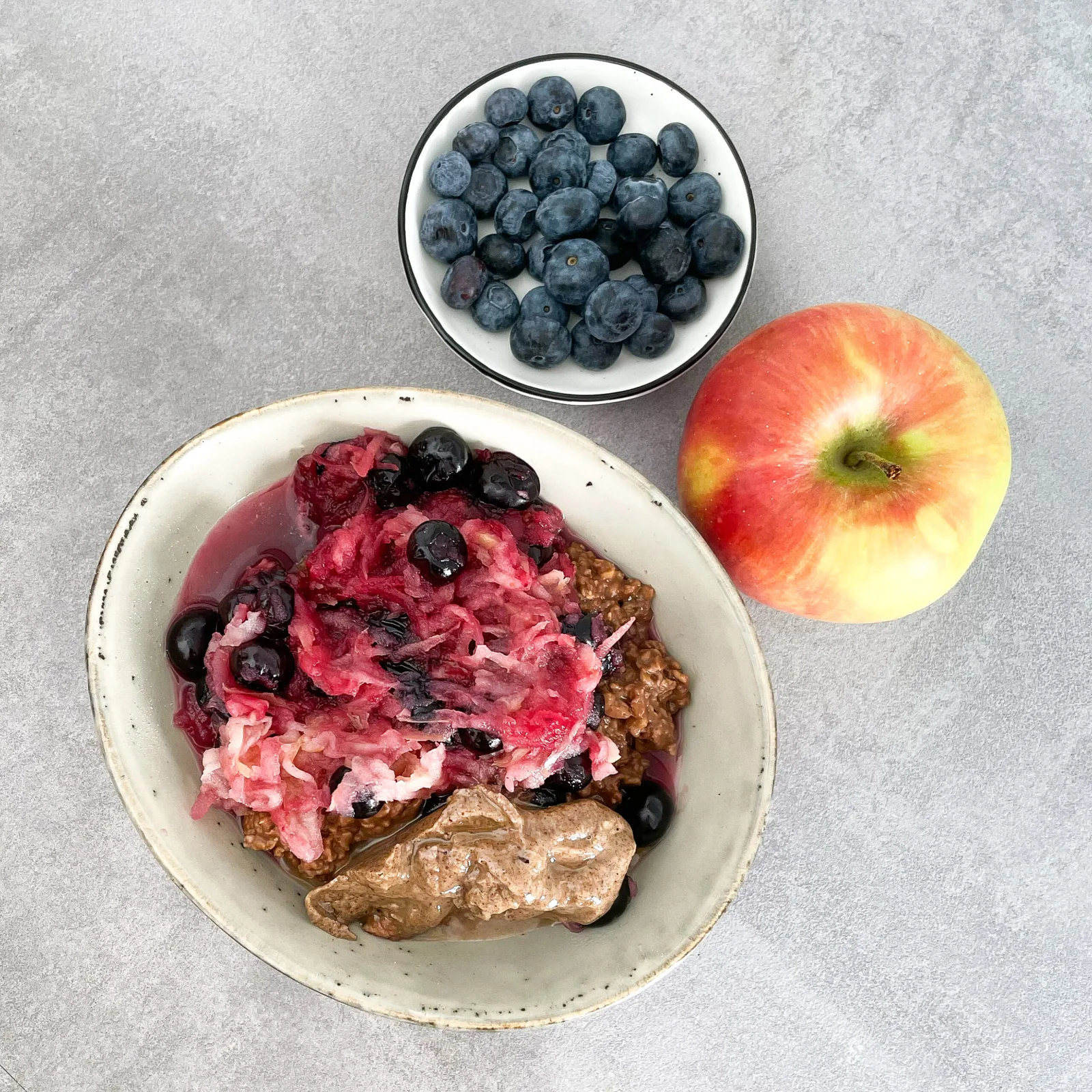 Blaubeer-Apfel-Kakao-Porridge mit Erdnussbutter und frischen Beeren