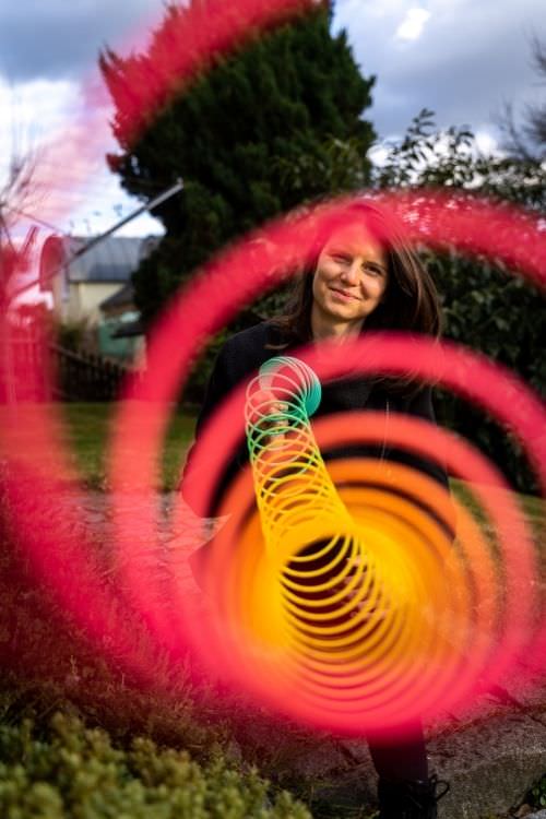 Frau mit leuchtendem Spiralenmuster in Pink und Gelb, Langzeitbelichtung