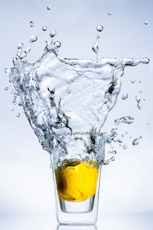 Wasser mit gelbem Objekt spritzt aus Glas, Hochgeschwindigkeitsaufnahme