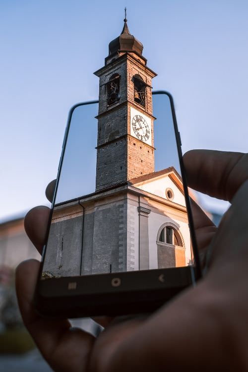 Kirchturm mit Uhr in Händen, fotografiert durch Smartphone-Rahmen