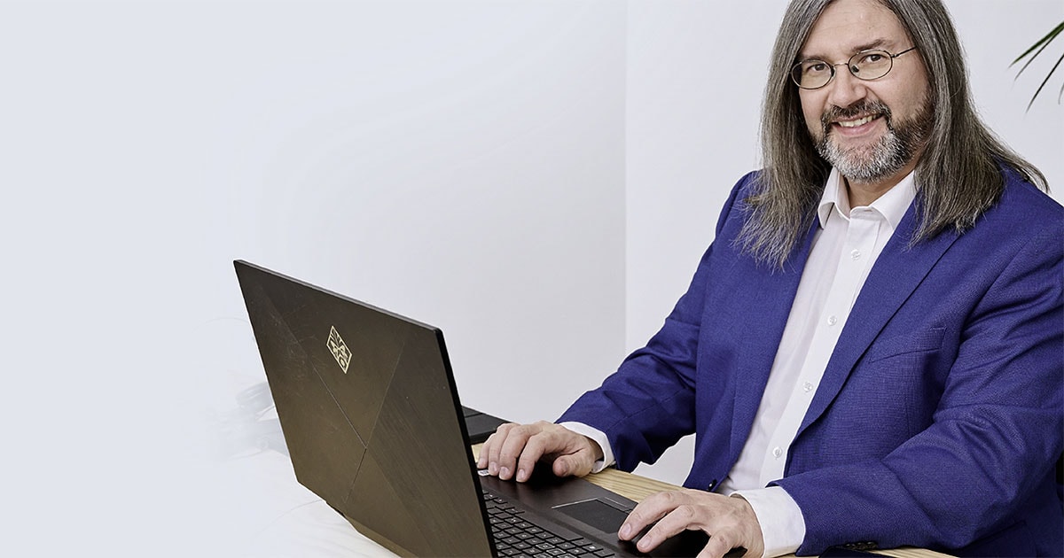 Michael Smetana mit Laptop, Mann mit grauem Haar, blauem Sakko