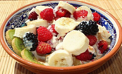 Quinoa-Schale mit Banane, Beeren und Kokosflocken in dekorativem Teller