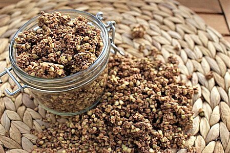 Granola-Mischung in Glas und auf Strohunterlage verteilt