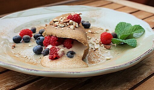 Süßer Buchweizen-Crepe mit Beeren und Nüssen auf weißem Teller