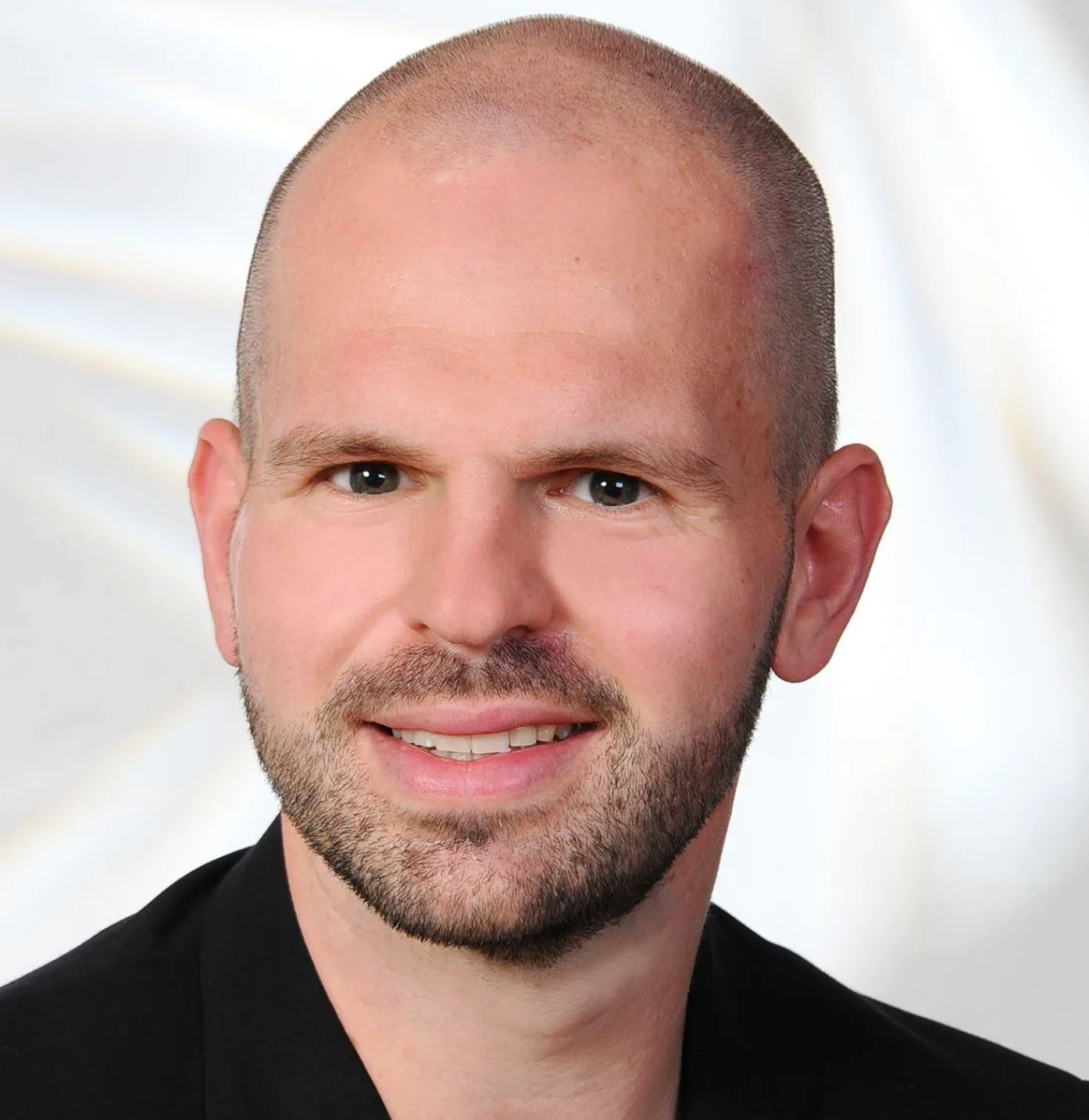 Portrait eines lächelnden Mannes mit Bart im schwarzen Hemd