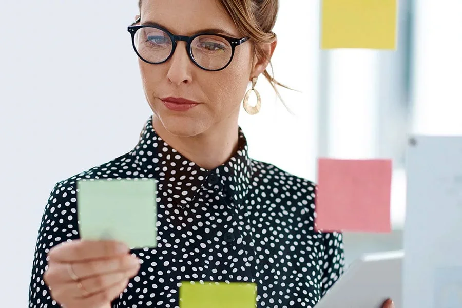 Frau mit Brille in gepunktetem Hemd mit grüner Notiz, 1-on-1 Coaching Landingpage
