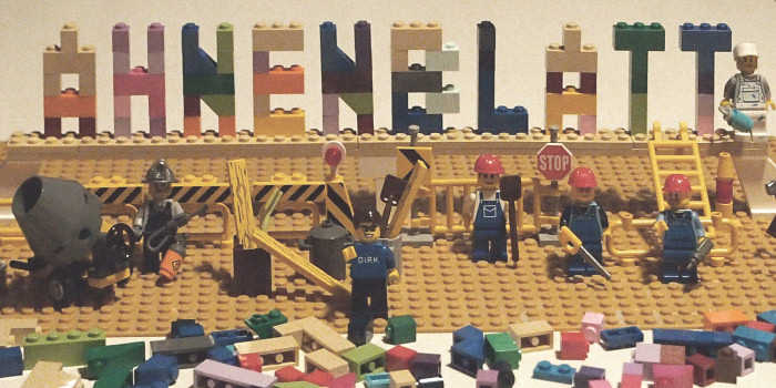 LEGO-Nachbau des Ahnenblatt-Logos mit Bauarbeitern und Baustelle, kreative Produktillustration