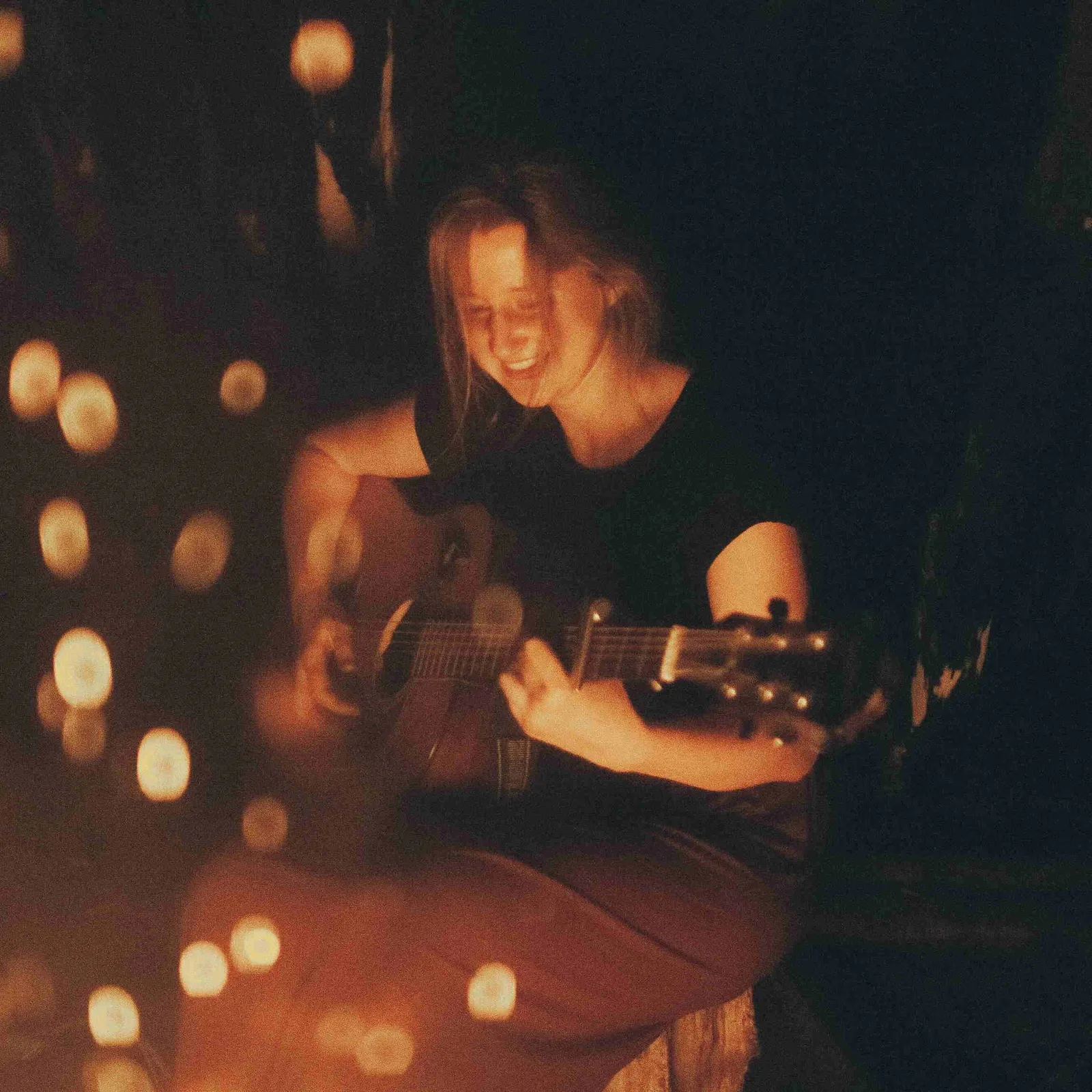 Gitarrenschülerin Sigrid spielt Akustikgitarre nachts mit warmem Kerzenlicht-Ambiente – Erfolgsstory Testimonial