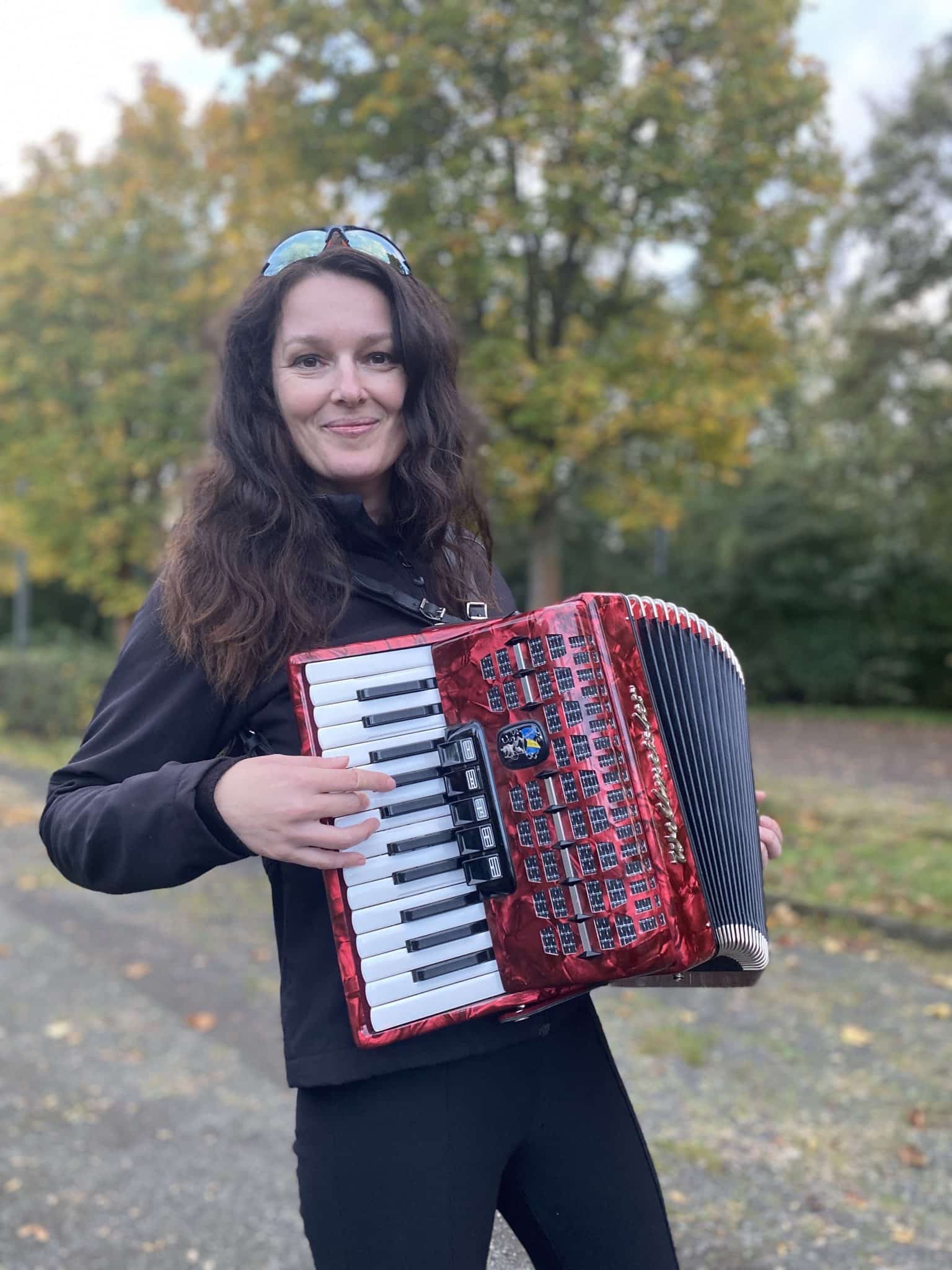 Lysann mit roten Akkordeon im Park, stolz nach Masterclass-Abschluss