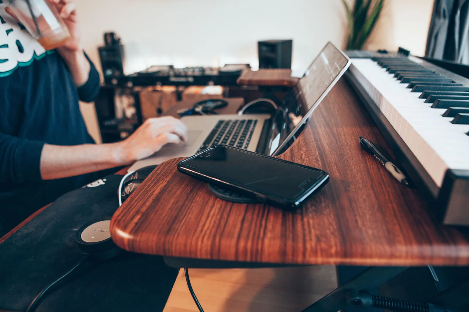 Home-Studio mit Keyboard, Laptop, Smartphone auf Holztisch, Musiker bei der Arbeit