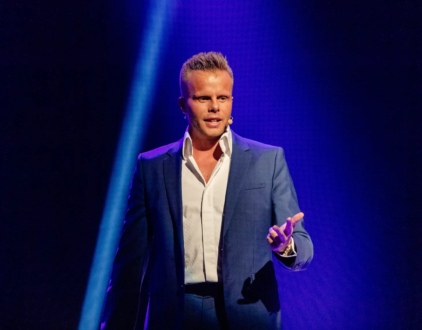 Gunnar Kessler präsentiert auf Bühne mit blauem Licht und Mikrofon