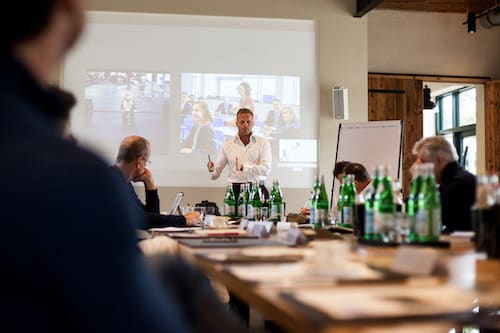 Gunnar Kessler präsentiert vor Gruppe in Konferenzraum mit Beamer