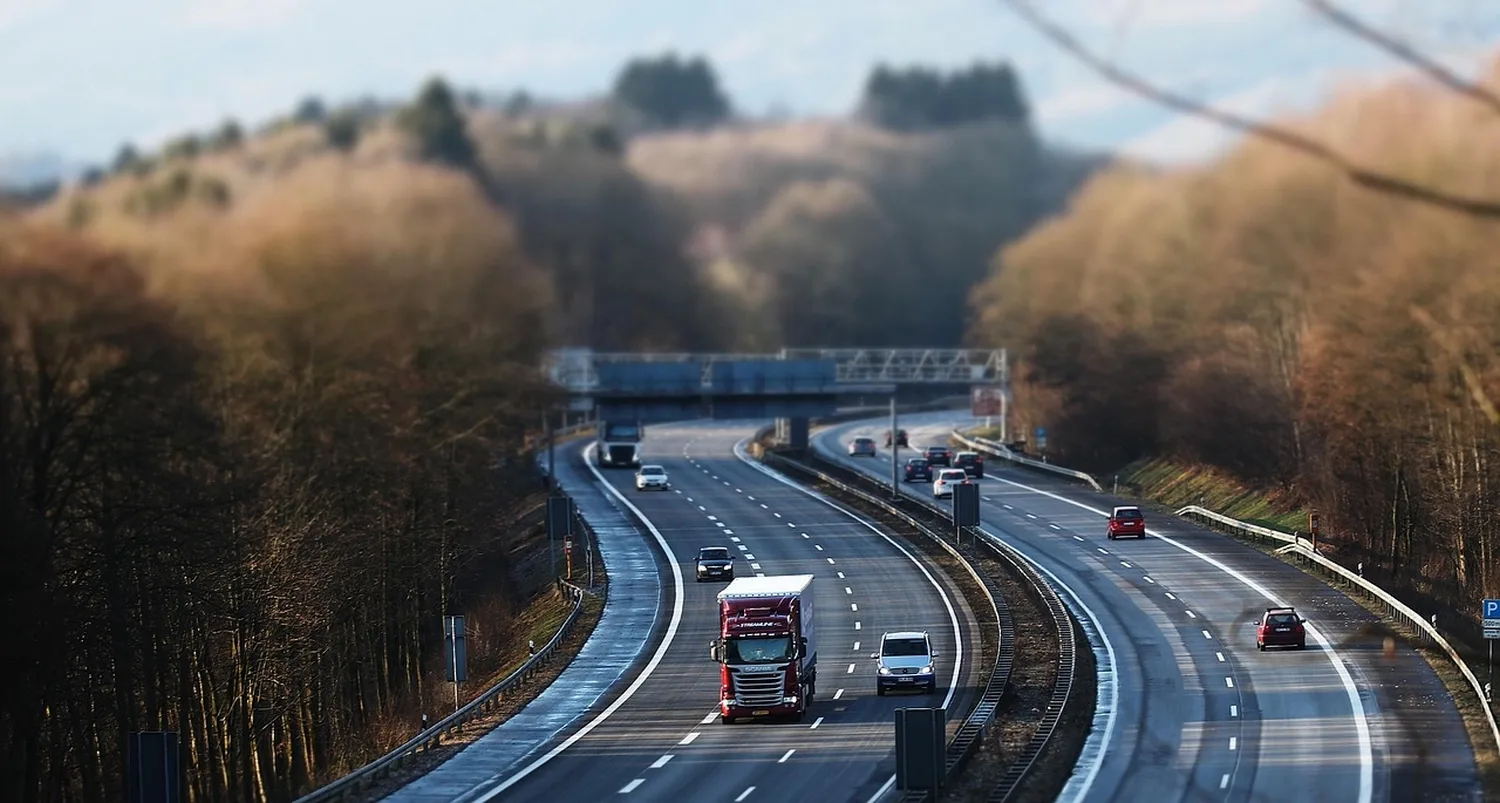 Autobahn mit mehreren Fahrzeugen von oben, Brücke, Waldkulisse, fokussierter Verkehr