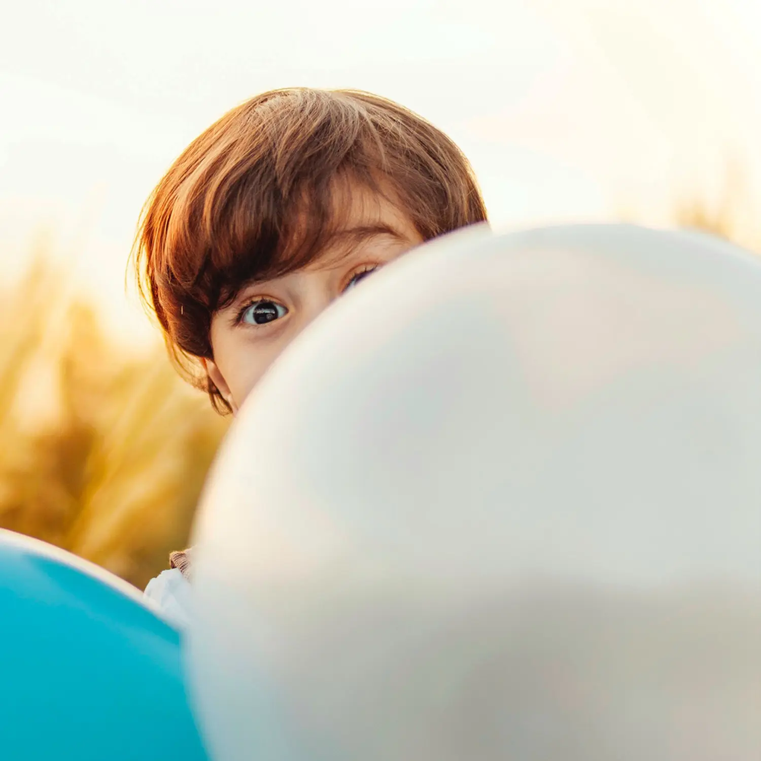 Angst – Hypnose-Hörbuch für Kinder von Christiane Krejczi 2 Kind mit rötlichem Haar späht hinter großem weißem Luftballon hervor vor unscharfem gelbem Hintergrund