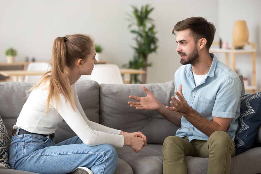 Paar sitzt auf Sofa und unterhält sich intensiv, Austausch und Kommunikation