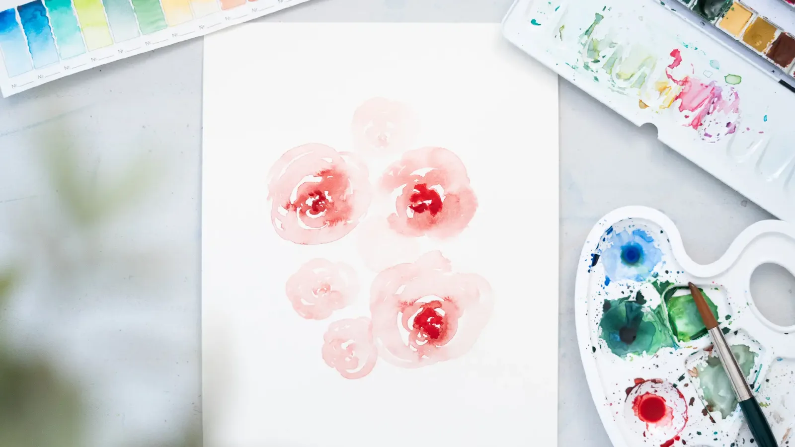 Aquarell-Blütenmotive in Rot und Rosa mit Farbpalette und Pinsel