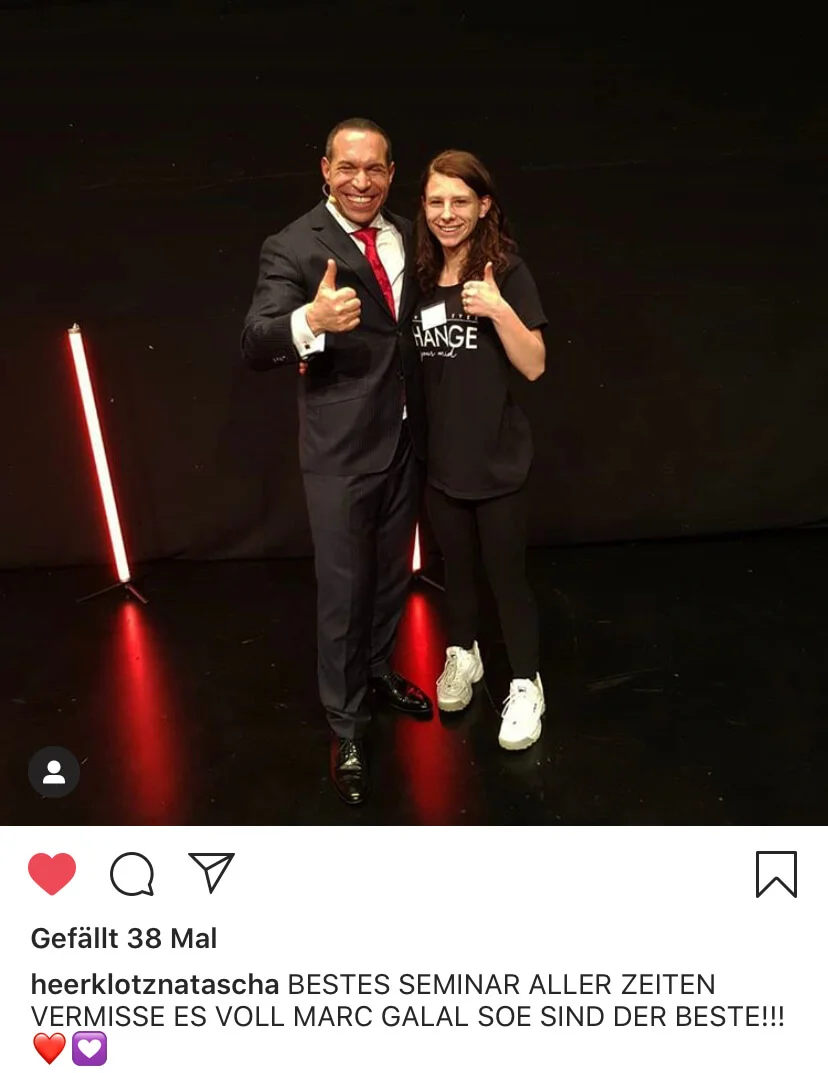 Marc Galal und Frau mit Daumen hoch vor schwarzem Hintergrund mit roten Neonlichtern, Seminar-Fotografie