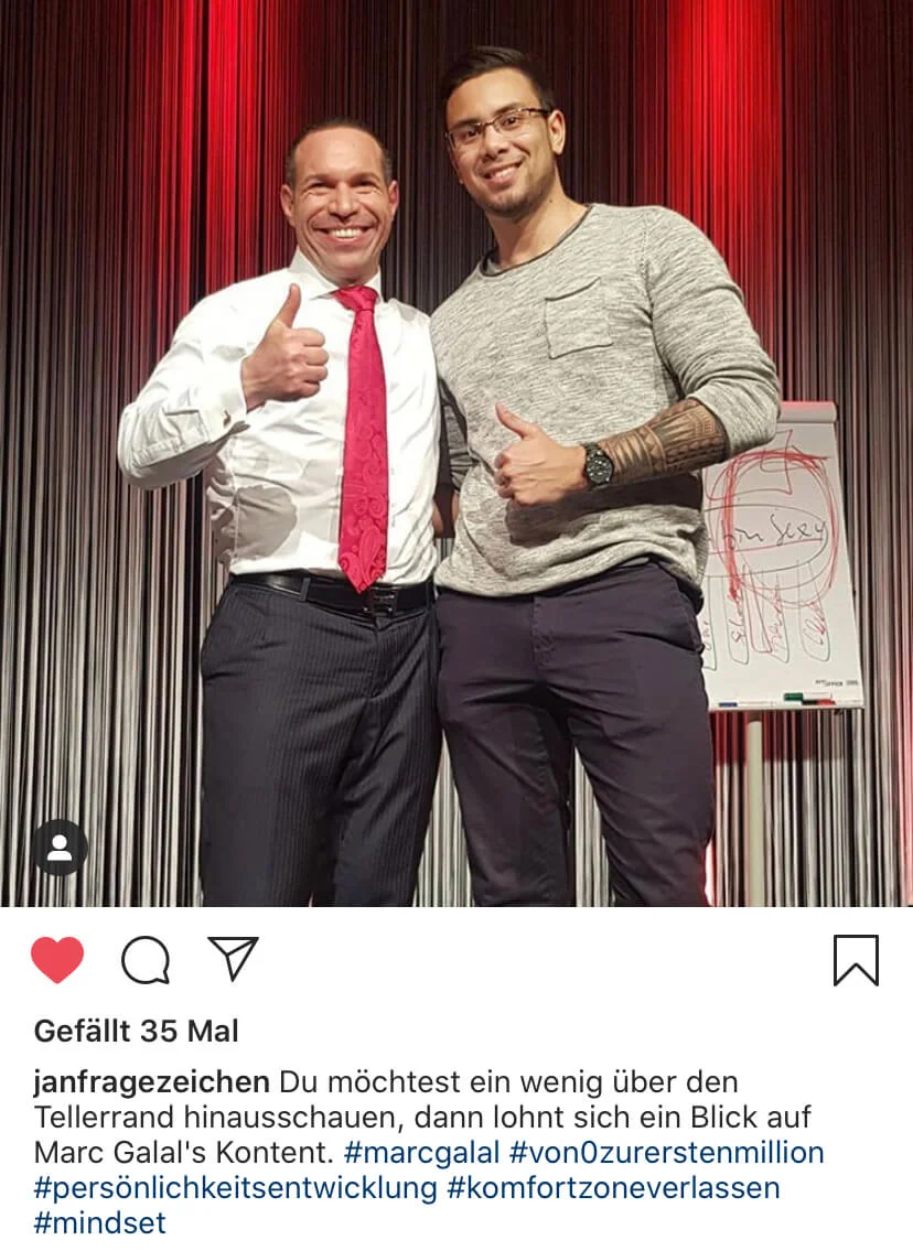 Marc Galal und Mann mit Daumen hoch vor roten Vorhängen, Flipchart sichtbar