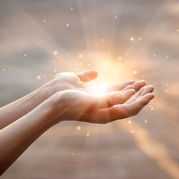 Zwei Hände mit Energielicht zwischen Handflächen, Heilungsenergie symbolisierend