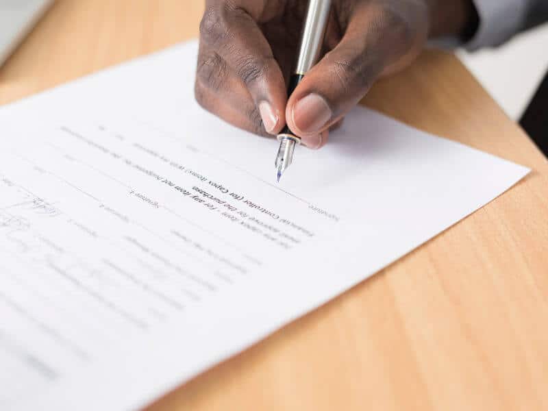 Auftragsverarbeitungsvertrag – Vertragsvorlage nach DSGVO 1 Hand unterzeichnet Auftragsverarbeitungsvertrag mit Füllfederhalter auf Holztisch