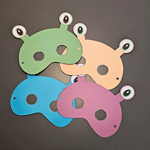 Vier bunte Monstermasken aus Karton in Grün, Beige, Blau und Rosa mit Augen