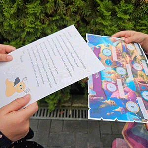 Kinder halten Missionskarten und bunte Monsterschnitzeljagd-Materialien in den Händen