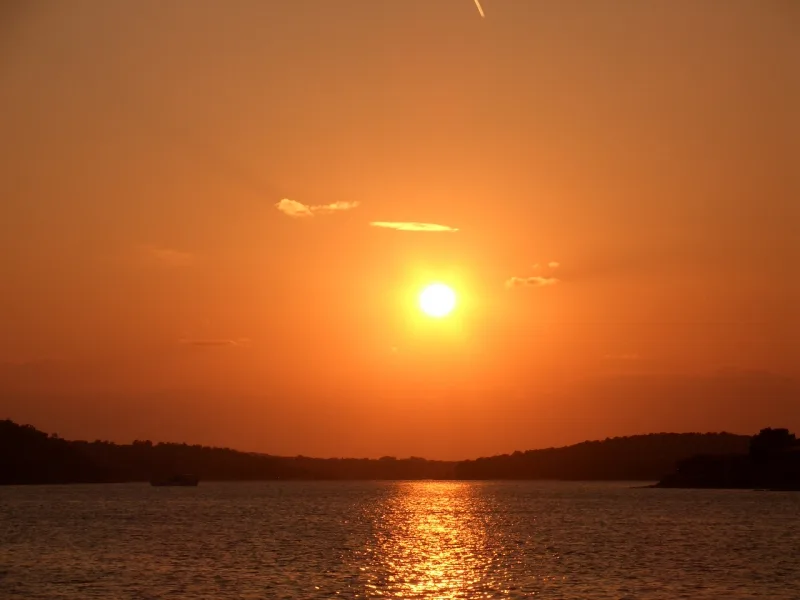 Sonnenuntergang über Wasser mit orangegoldenem Himmel und Spiegelung