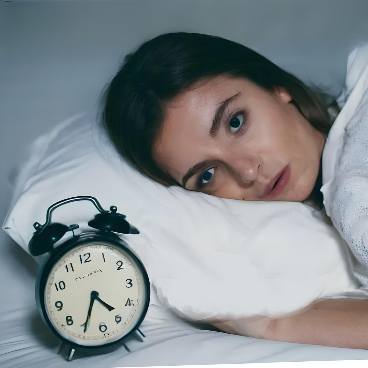 Frau liegt wach im Bett mit Wecker, kann nicht schlafen, zeigt Schlaflosigkeit