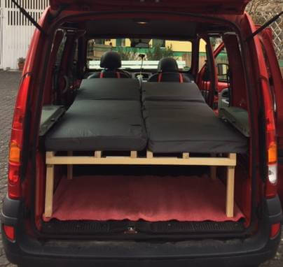 Roter Van mit eingebautem schwarzem Doppelbett und Stauraum darunter