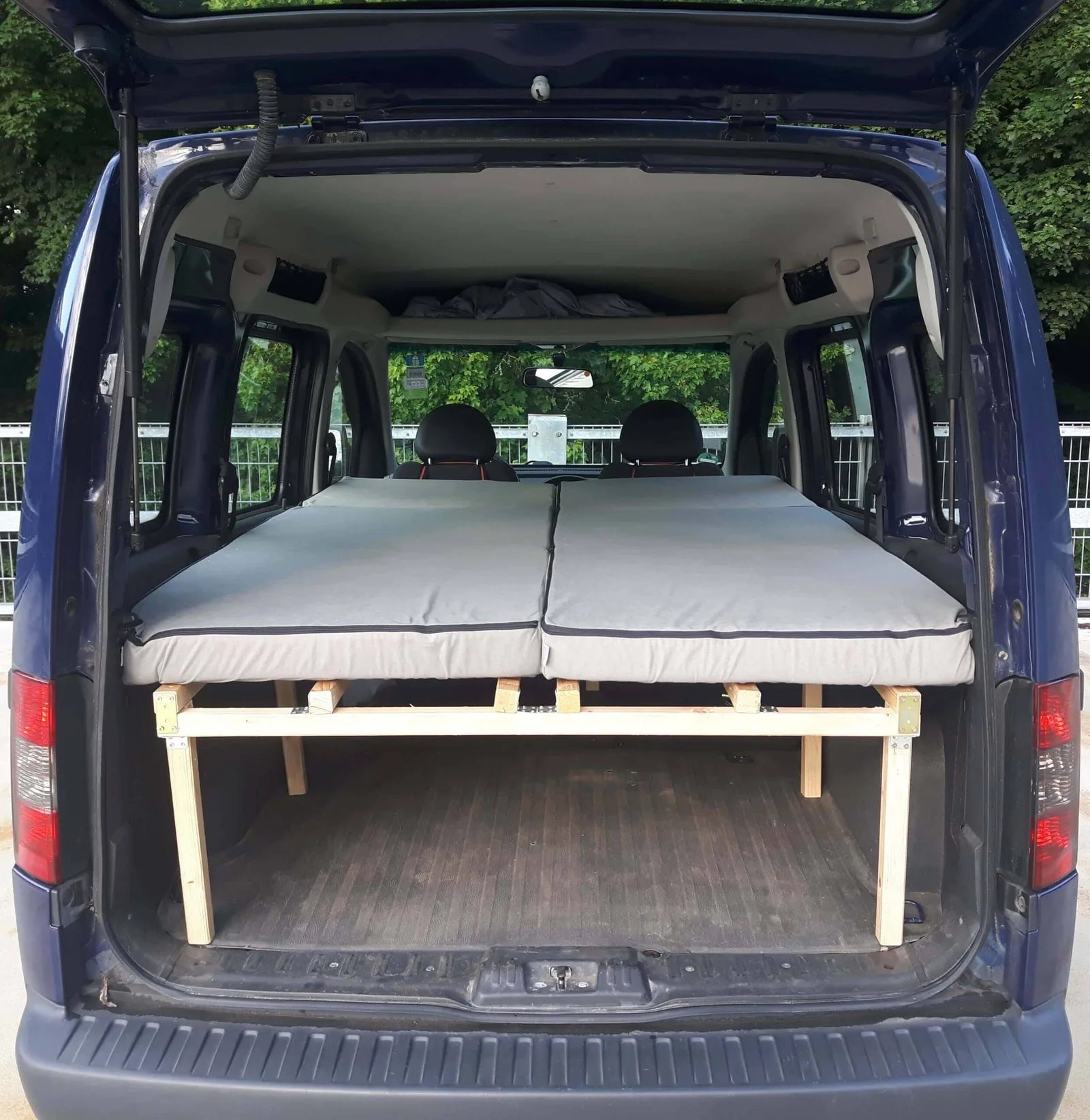 Opel Combo C mit ausgezogenem Einzelbett, Matratze und Holzgestell sichtbar