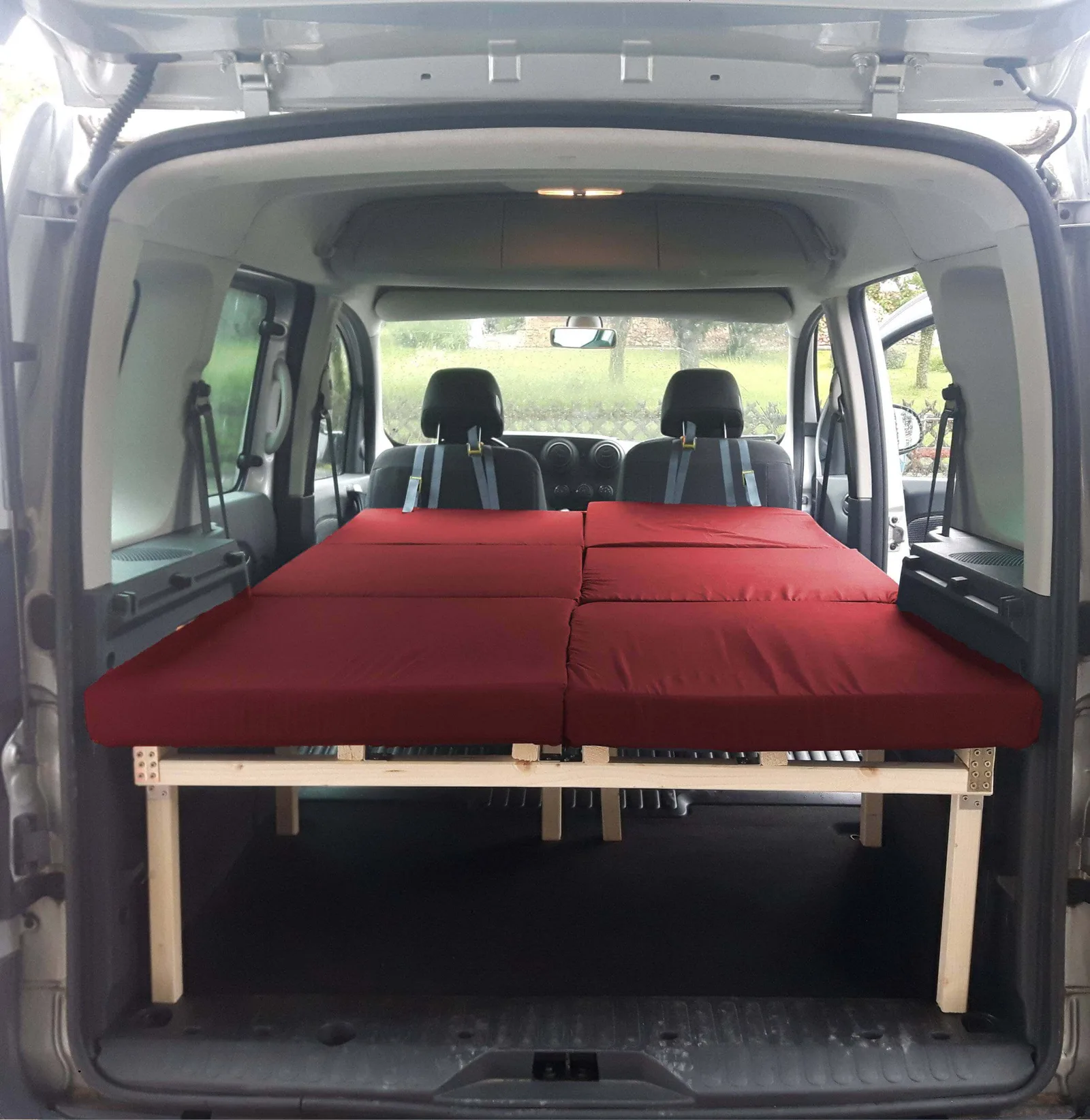 Rotes Doppelbett in Renault Kangoo W mit Holzrahmen und Matratze, Innenansicht des Fahrzeugs