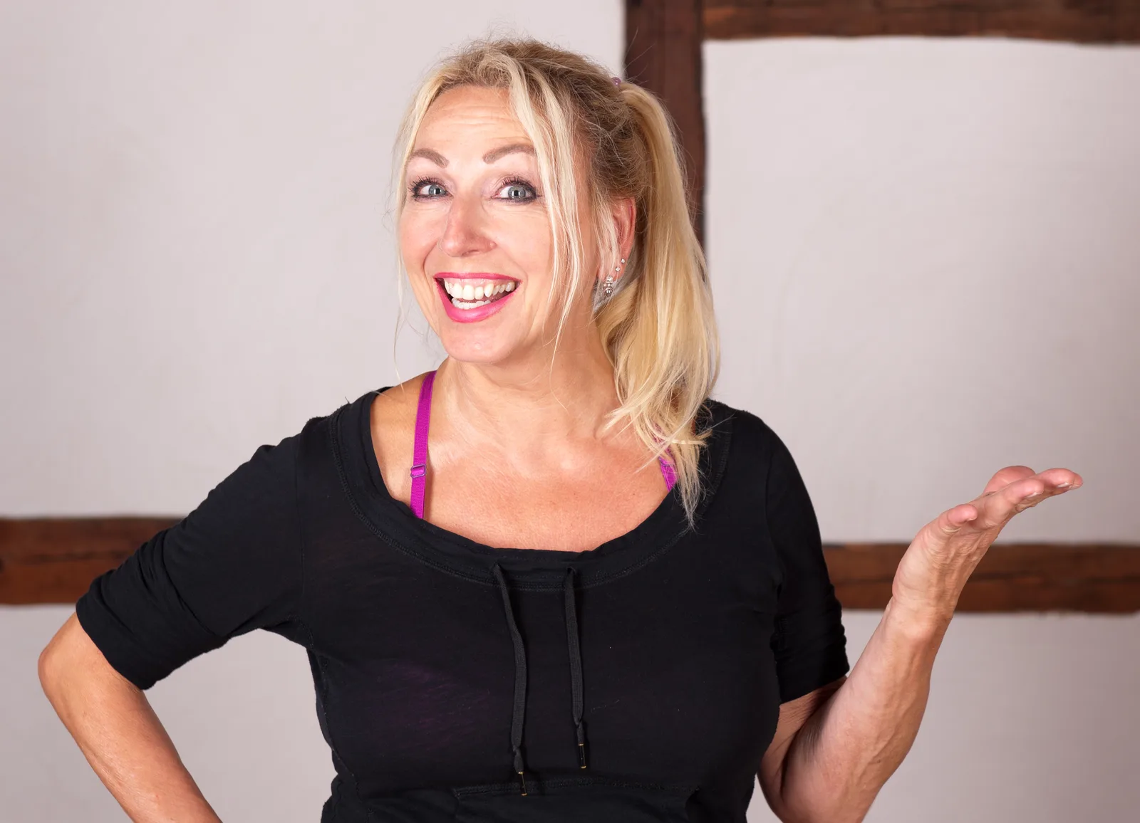 Gabriela Höper Portrait, blonde Frau in schwarzem Shirt mit lila Accessoire, lachend