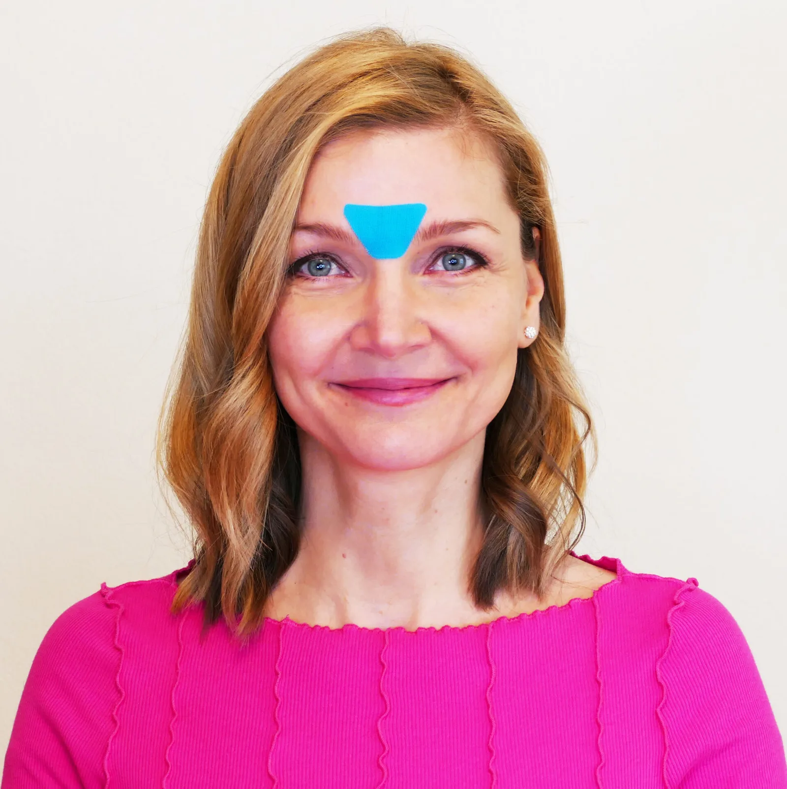 Beauty Taping – Videokurs zur Gesichtsstraffung von Christina Schmied 5 Frau mit blauem Beauty Tape auf der Stirn zwischen den Augenbrauen, Anwendungsbeispiel