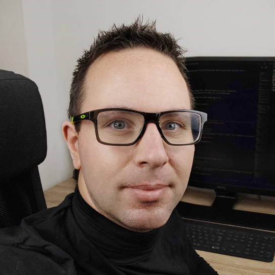 Porträtfoto von Niko Strobel, Mann mit Brille und schwarzem Rollkragenpullover in Büroumgebung