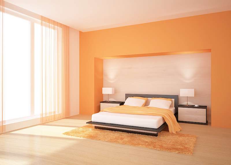 Modernes Schlafzimmer mit orangenen Wänden, schwarzem Bett, gelber Bettwäsche und Beleuchtung