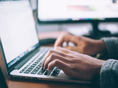 Hände tippen auf Laptop-Tastatur am Schreibtisch