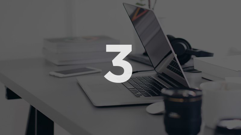 Schreibtisch mit aufgeklapptem Laptop und Tablet, große Nummer 3 zentriert