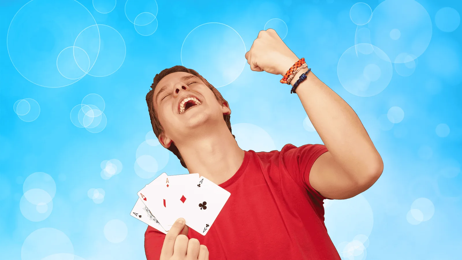 Junge im roten Shirt jubelt freudig mit Spielkarten in der Hand