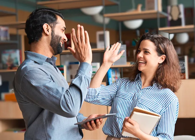 Mann und Frau geben sich zufrieden lachend ein High Five mit den Händen