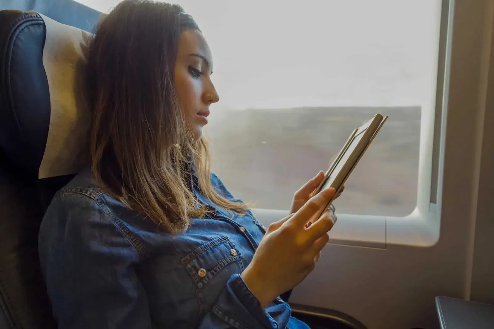 Blockaden lösen: Hypnose Audio-Kurs von Sebastian Haffner 1 Frau im Flugzeug liest auf Tablet am Fenster, Audio-Kurs Download