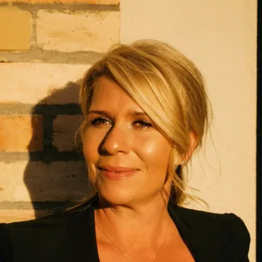 Brainwashed Priming – Videokurs für Morgenroutine von Gunnar Kessler 10 Porträtfoto einer Frau mit blondem Haar vor Backstein-Hintergrund