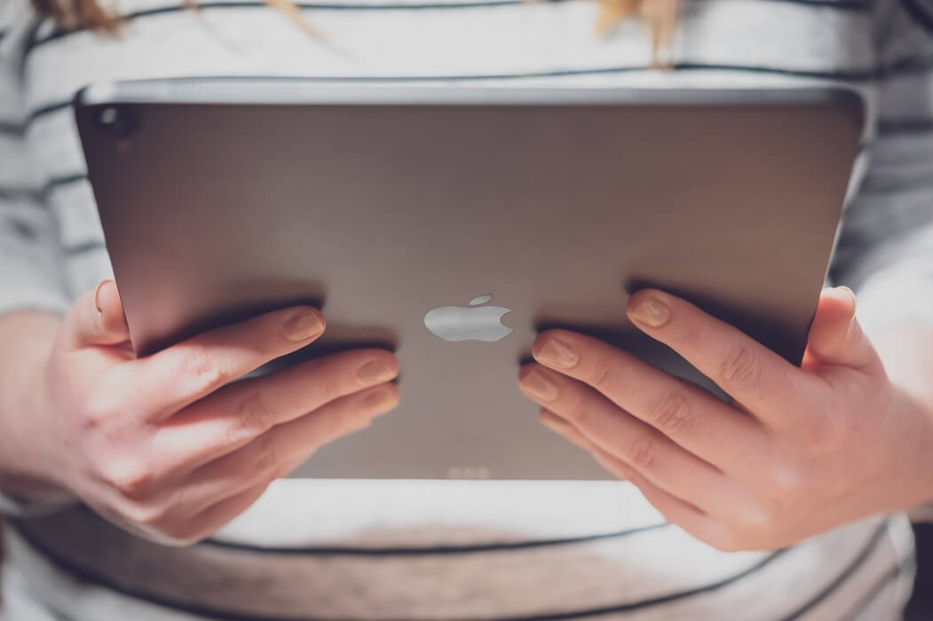 iPad in Händen haltend mit Apple-Logo
