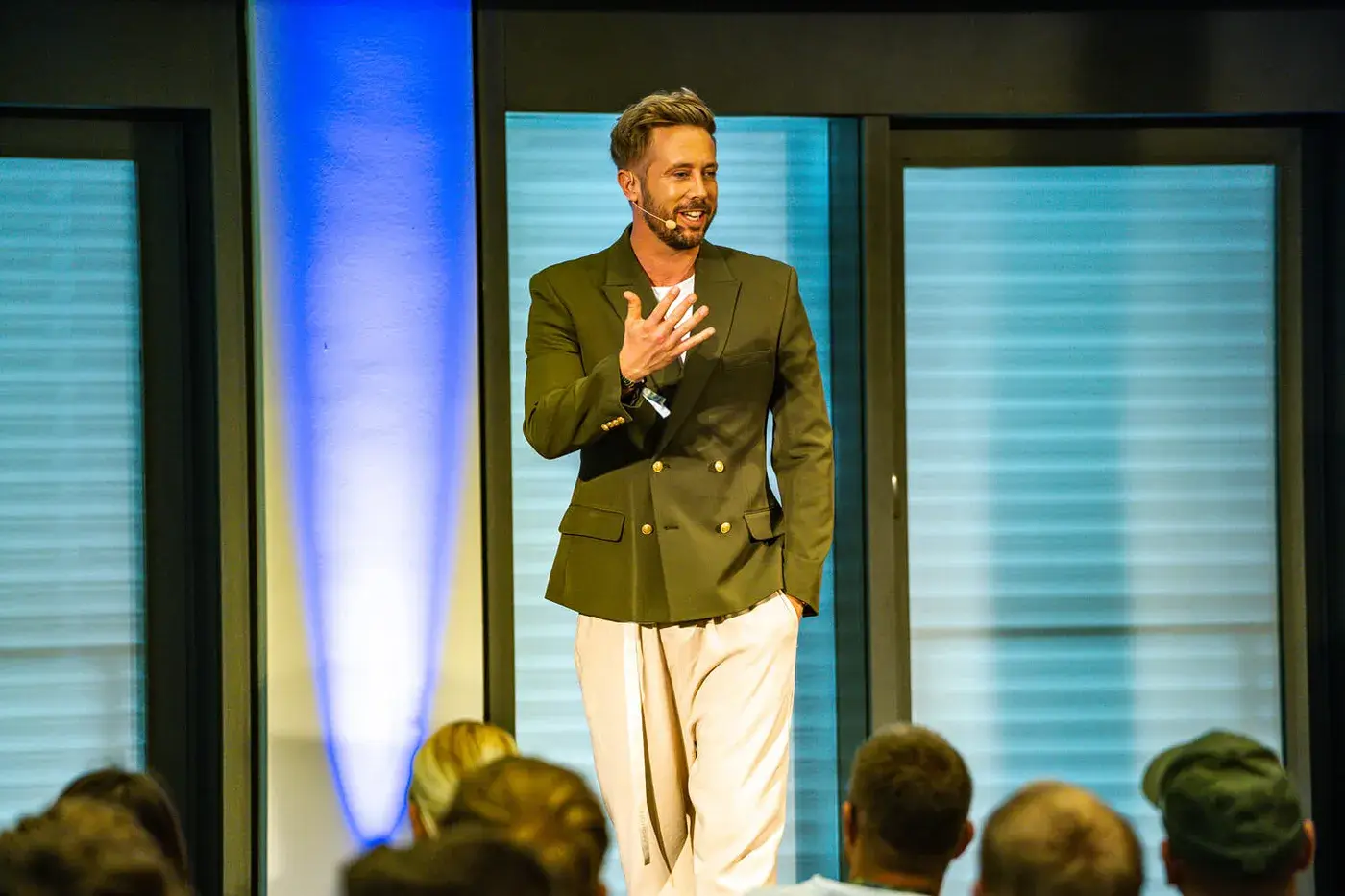 Felix Thönnessen in olive-grünem Blazer auf Bühne vor Publikum sprechend